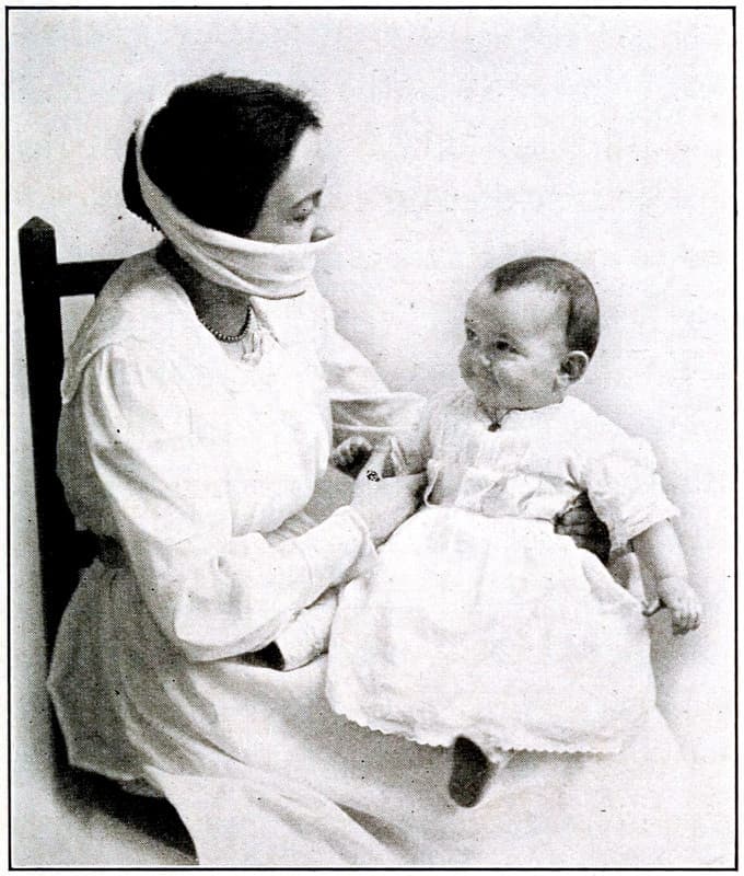 A woman wearing a mask covering their
mouth and nose while holding a baby